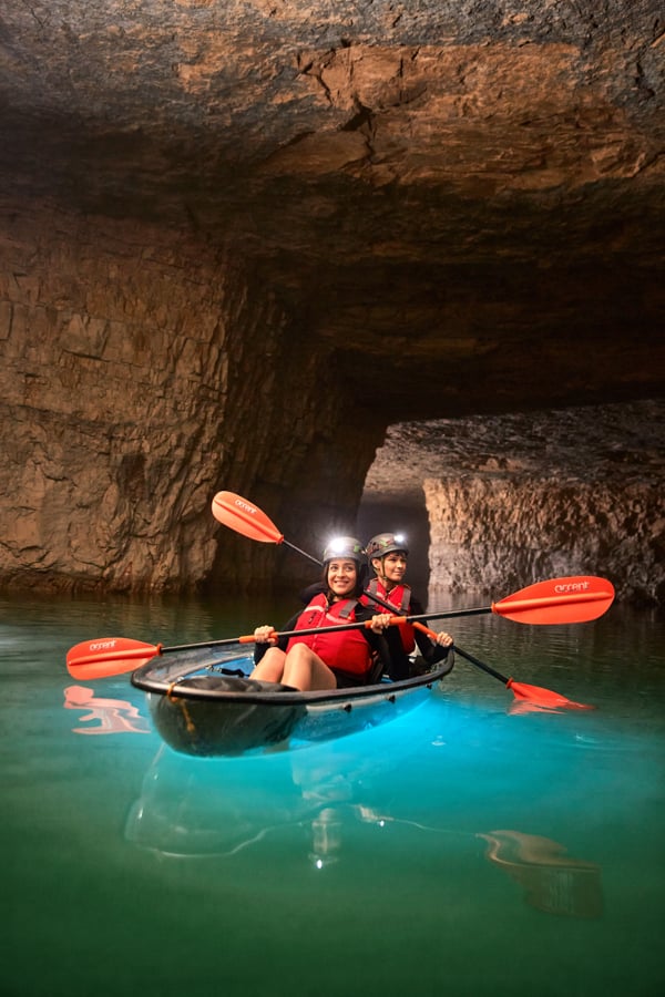 Portrait of two kayakers with headlamps traveling through a cave by Louisville, Kentucky-based photographer Clay Cook.