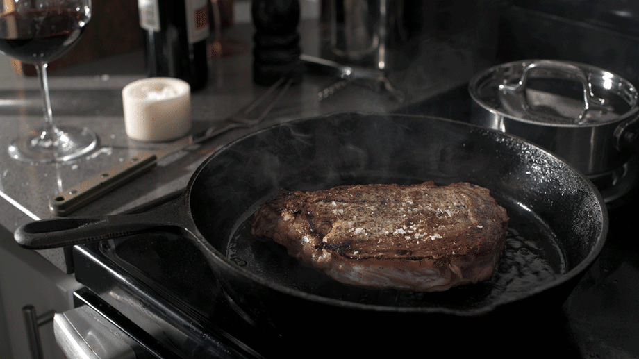 Shea Evans' shot of a steak cooking in cast iron, with steam rising and the oil shimmering in the pan