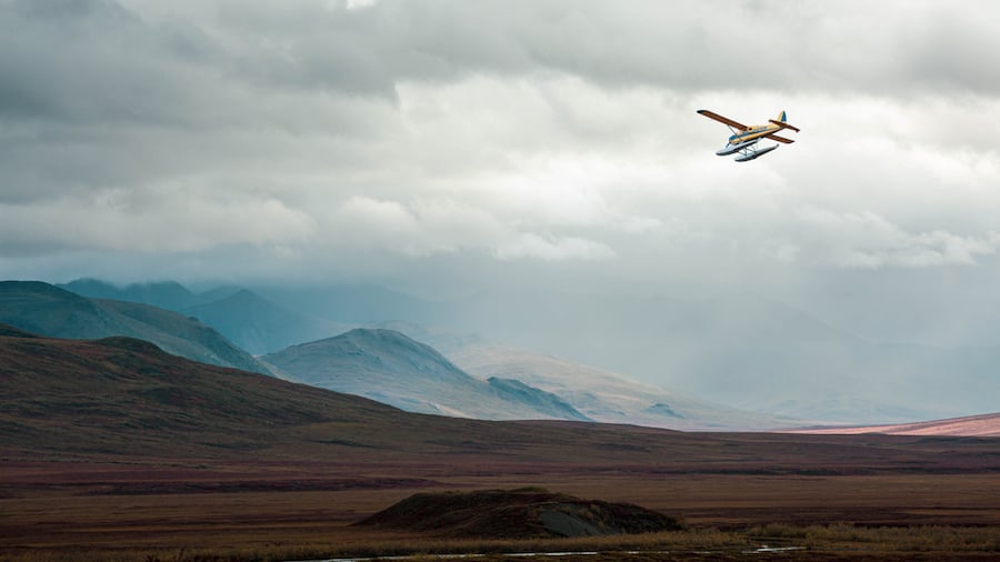 A small water airplane flying over mountains on a misty day by photographer Craig Okrasaka of Lander, Wyoming. 