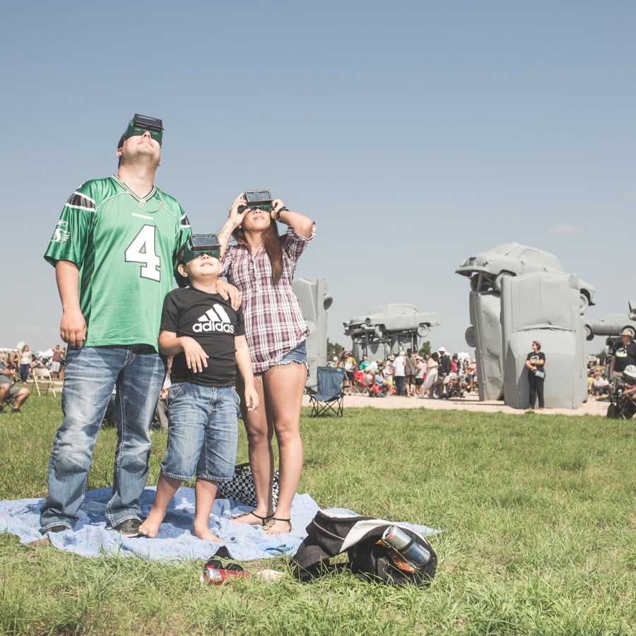A family looks up at a solar eclipse wearing special goggles by photographer D. Scott Clark of Denver, Colorado