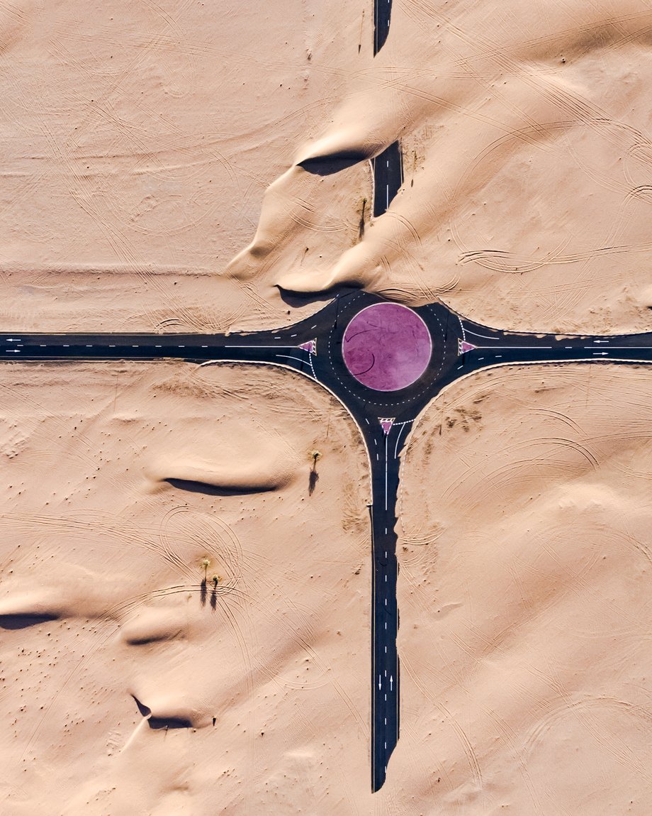 Photo by Irenaeus Herok of an overhead view of a road overrun by desert sand.