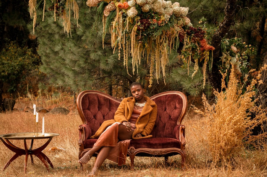 Jesse Cornelius' wide angle image of a Black woman reclining on a couch in an outdoor setting for Solmonson Farms
