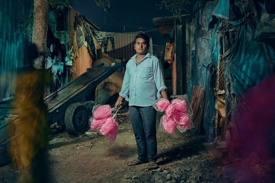 Portrait of candy floss vendor holding cotton candy for sale in both hands by London-based portrait photographer Jon Enoch.