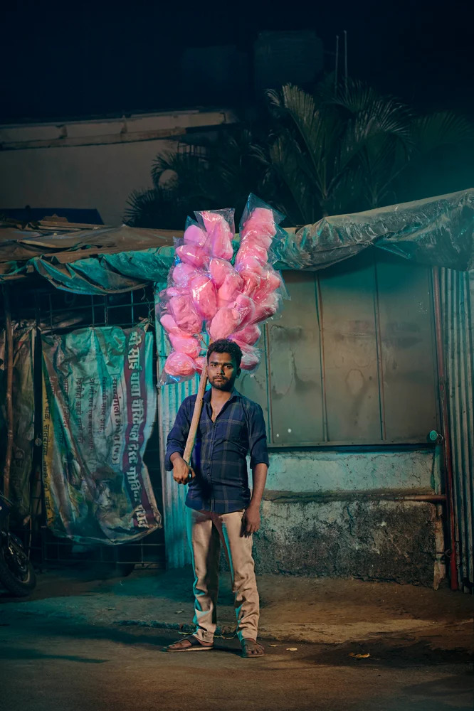 Photo of candy floss vendor standing on Mumbai street at nighttime by London-based portrait photographer Jon Enoch.