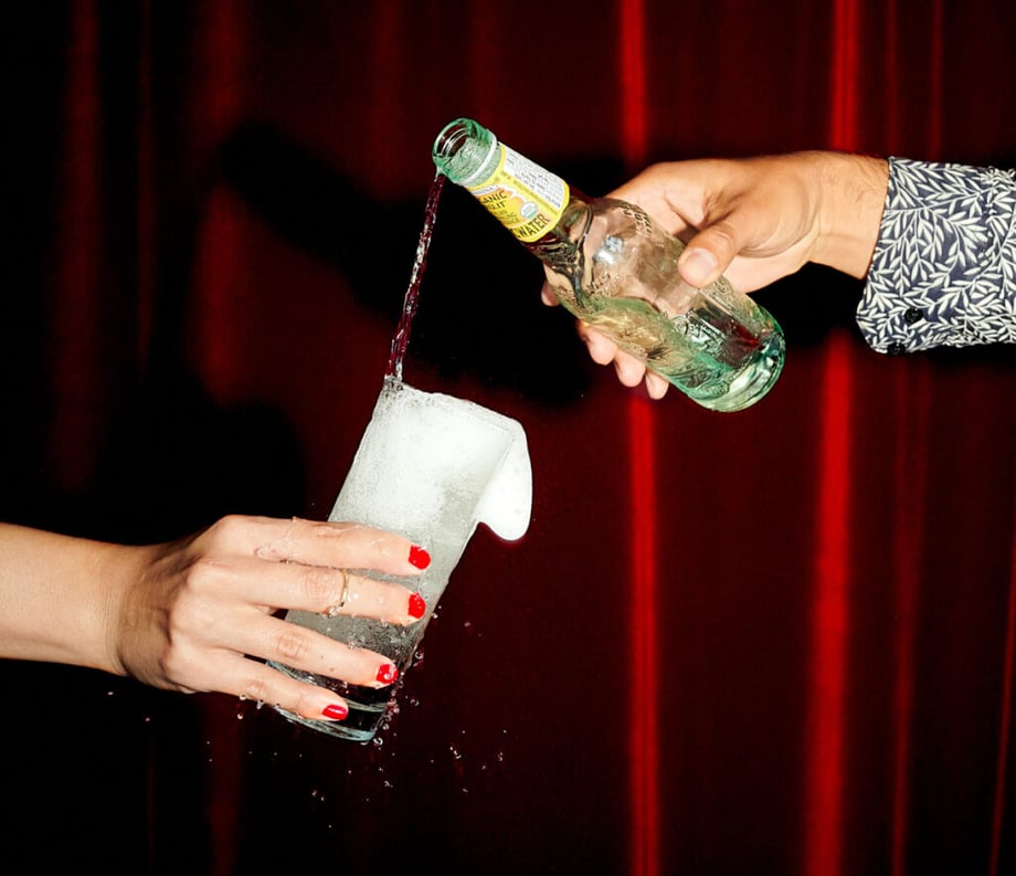 Somebody pouring seltzer water into another persons drink by photographer Joseph Weaver