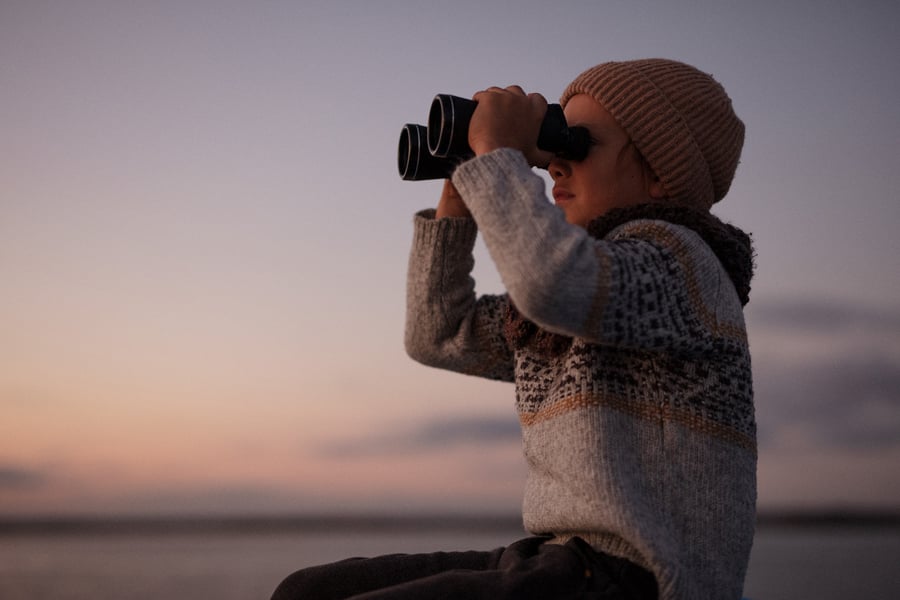 A child looks through binoculars into the distance by photographer Joshua Behan of Westerly Rhode Island