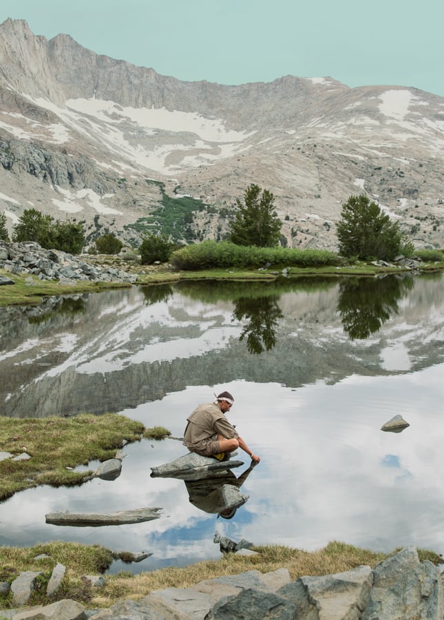 Image of a figure crouching at mountain lakeside by Dallas, Texas-based photographer Justin Clemons.