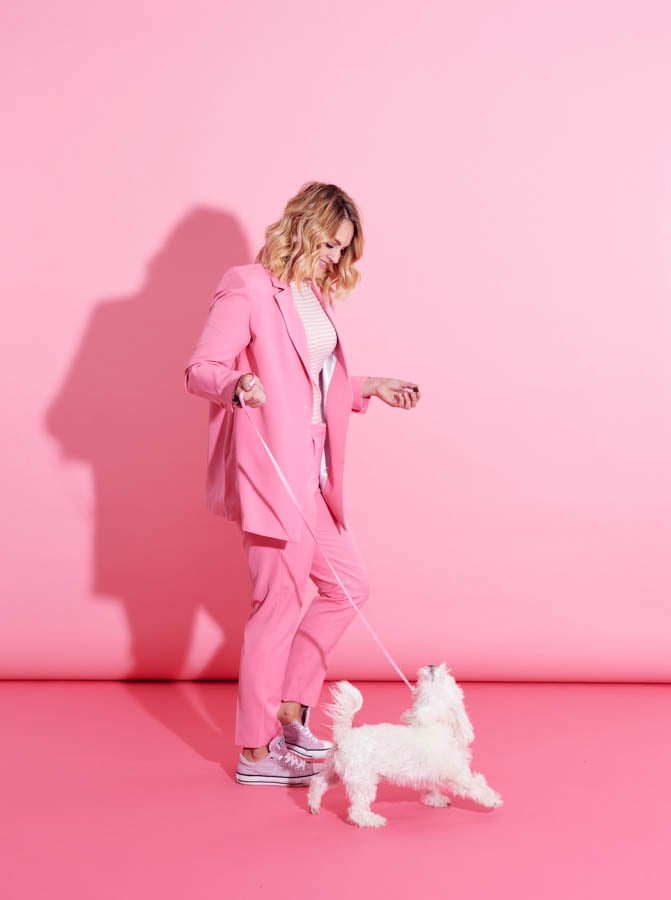 a woman in all pink walks her fluffy white dog in front of a pink back drop by photographer Lauren Pusateri of Kansas City, Missouri 