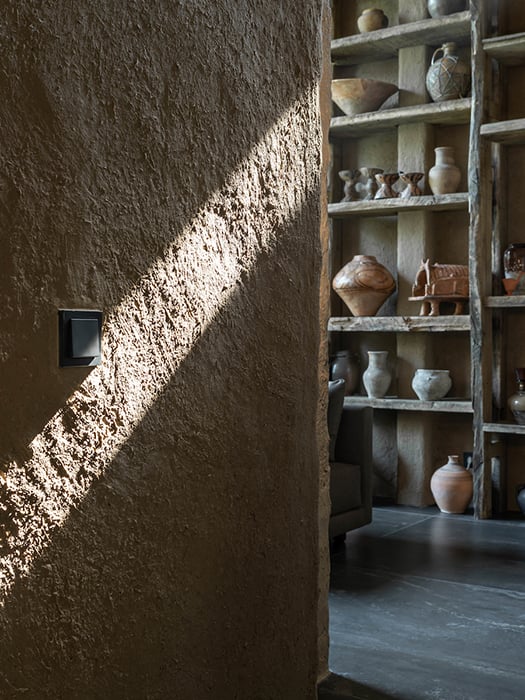 A beam of sunlight on the wall, ceramics in the background on a shelf