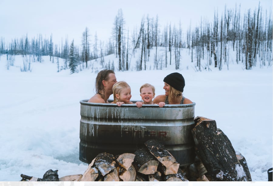 Image of parents and two children in trough-hot tub during a snowy winter by Whistler, Canada-based photographer Michael Overbeck.
