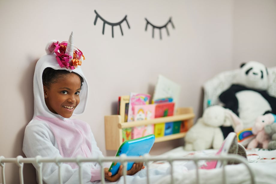 Natalia Weedy Calix a Black child dressed in a unicorn costume being pacified by an iPad