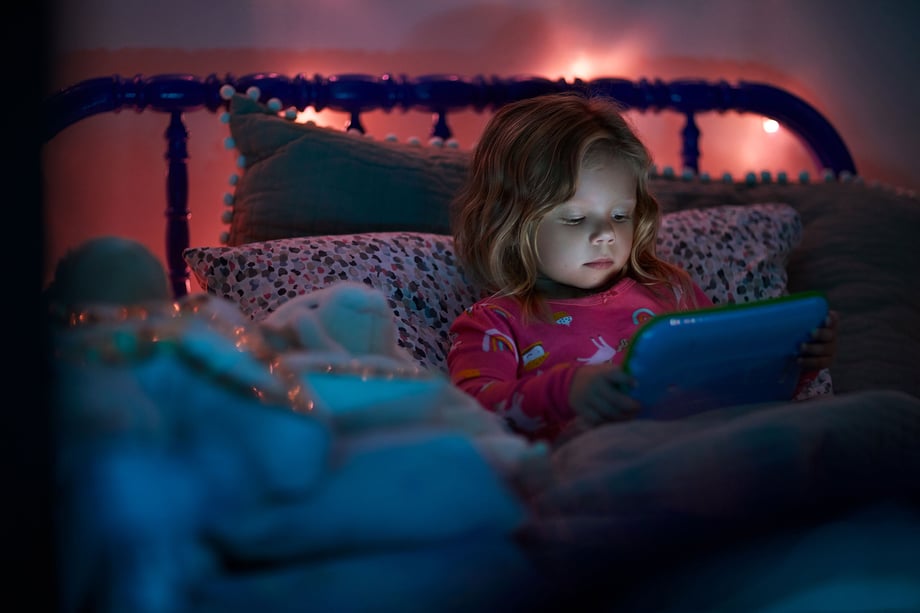 Natalia Weedy Calix a young White child in bed at night using a device rather than sleeping