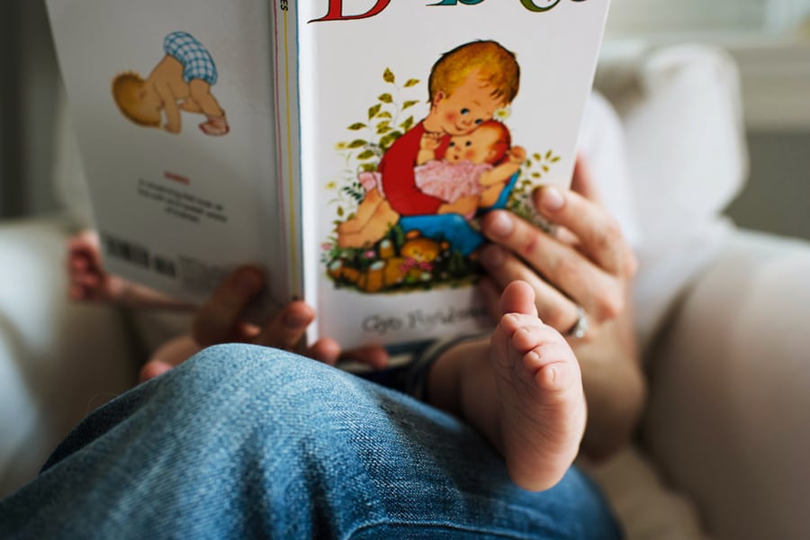 A small baby sits on their parents' lap as they read them an ABC book by photographer Nicole Loeb of Boston, Massachusetts