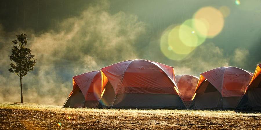 Photo of tents at a dusty campsite with tree and solar flares by Coppell, Texas-based photographer R.J. Hinkle.