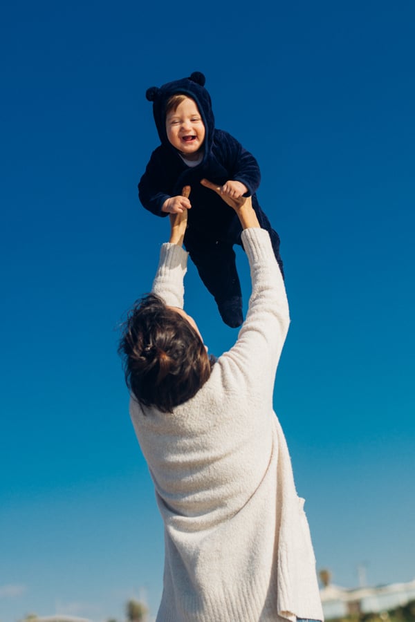 A man holds up his laughing toddler as the clear blue sky radiates behind them by photographer Ronen Goldman of Tel Aviv, Israel