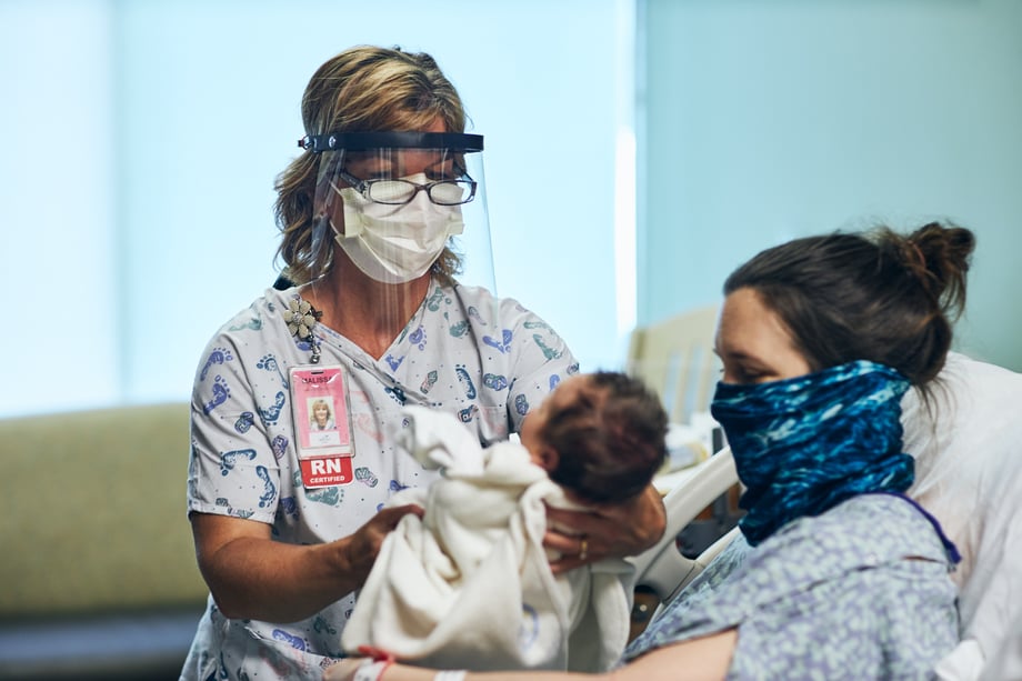 Ryan Smith's photo of a nurse in PPE and face shield assisting a mother with her newborn at Meritus Medical Center 