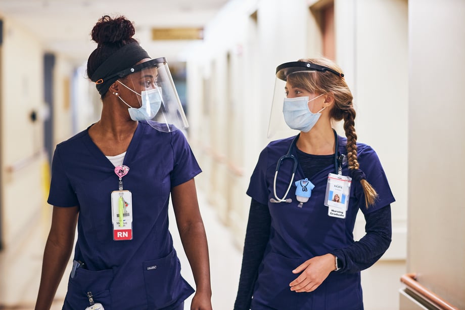 Nurses wearing surgical masks and face shields walking in the hallway of Meritus Medical Center photographed by Ryan Smith