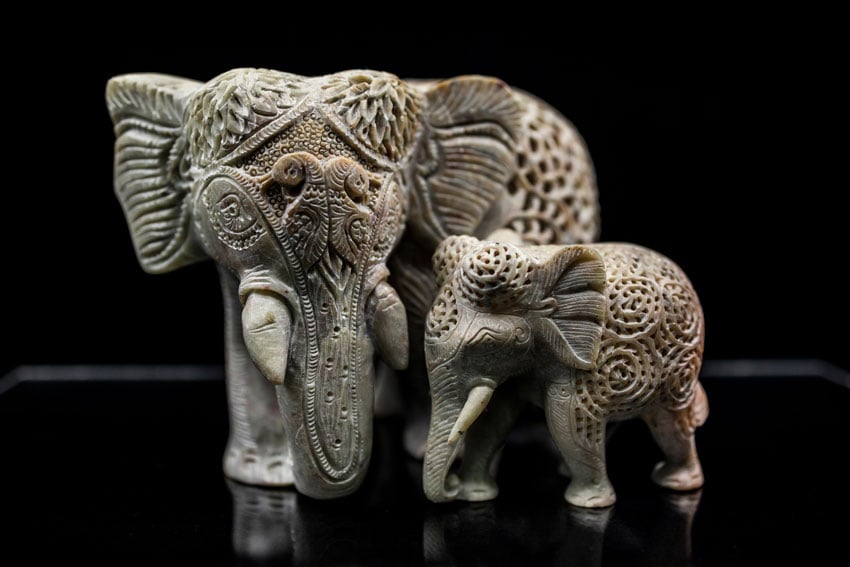 Hand-carved elephants sit against a black background in this photo by. Shea Winter