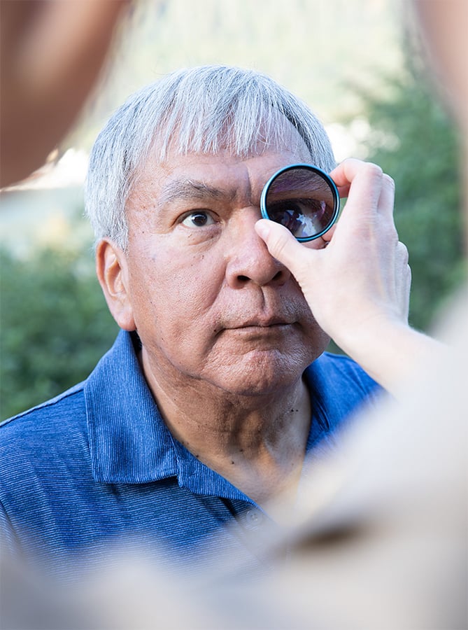 A person holds a magnifier up to an elderly mans eye by photographer Steve Craft of Pheonix, Arizona 