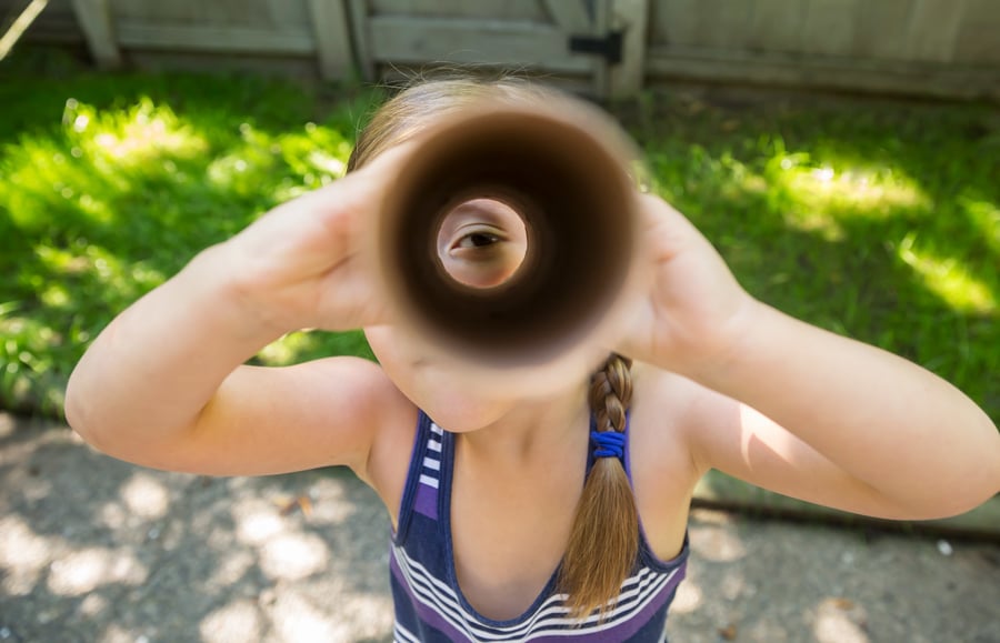 A young girl looks through a paper towel holder, showing her eye by photographer Steven Errico