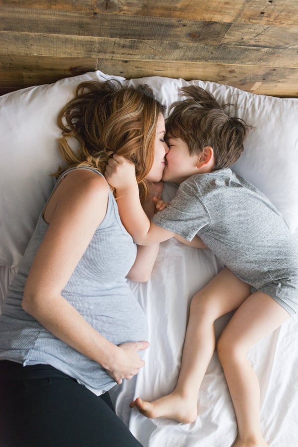 a pregnant mother kisses her son in bed by photographer Tenley Clark of San Jose, California