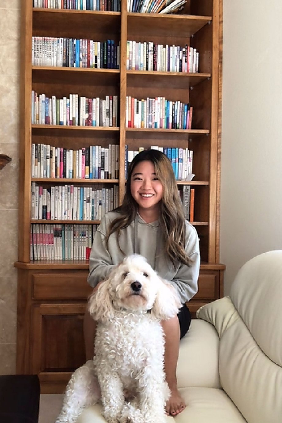Tom Kubik's image of an Asian woman with her dog in front of her bookcase for Bob Cut Mag Dog