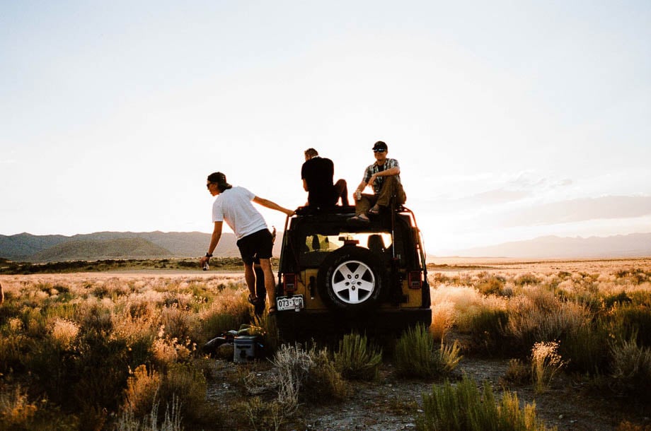 Photo of three friends hanging out in an open field on their jeep taken by San Francisco-based lifestyle photographer Adam Wells. 