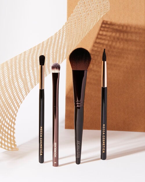 Photo by Amanda De Simon of four make up brushes standing up on their own.