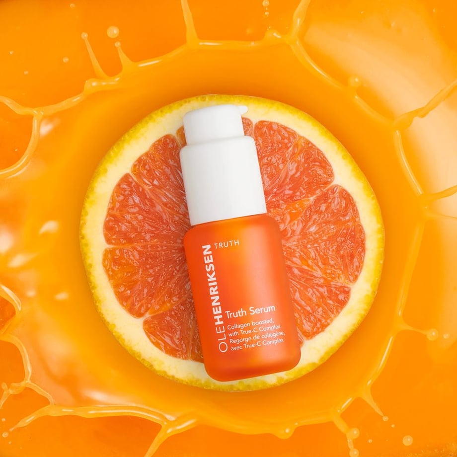 Photo by Amy Roth of a beauty product over an orange, sliced and splashing into an orange liquid for effect.