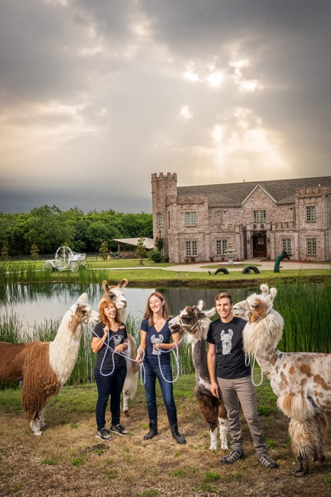 Three people and four llamas in front of a castle in Texas shot by Jeff Wilson.