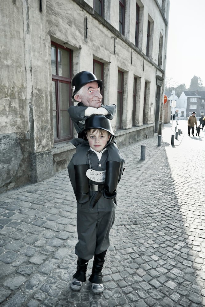 a young boy wears a police uniform with a police-dummy on his shoulders