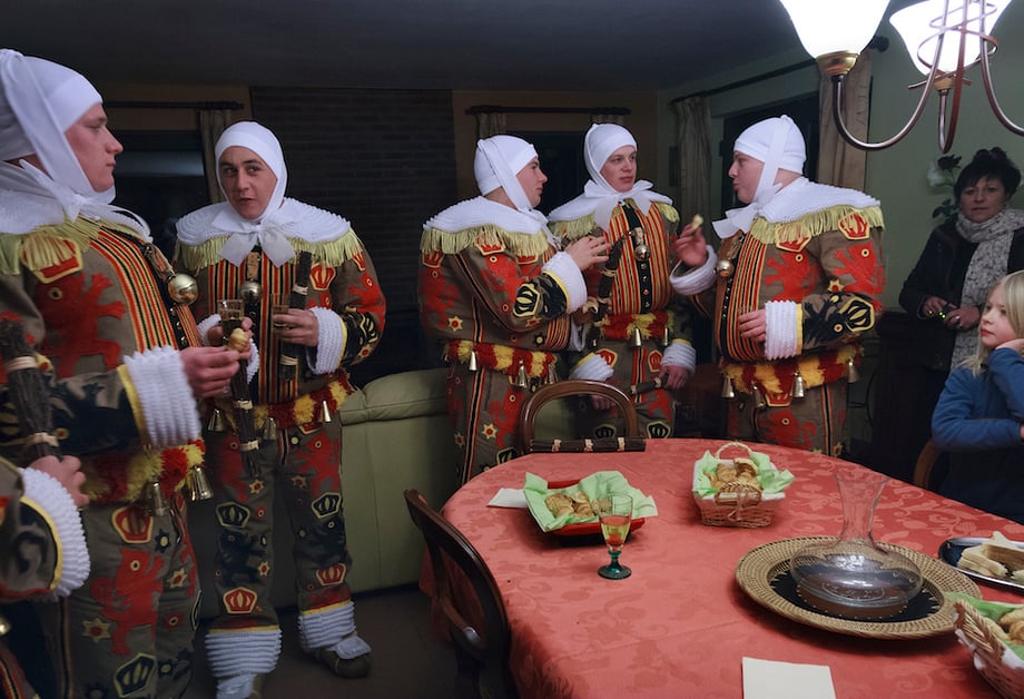 men in gille costumes of red yellow and black gather in a dining room