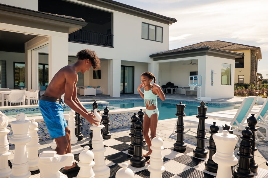 Photo by Brian Carlson of two siblings playing an over-sized chess game next to a pull.