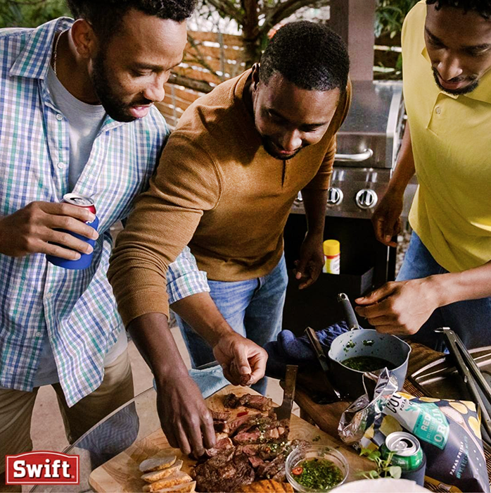 Three men gathering around and eating Swift Meats.