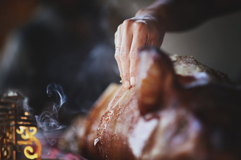 Photo of chef hand testing the skin of a roasted hog, by Singapore food photographer Carlina Teteris. 