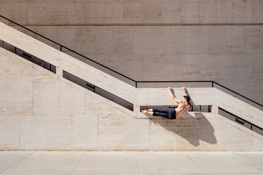 Image of figure suspending body from the side of a staircase, by Los Angeles fitness photographer Chris Ozer.