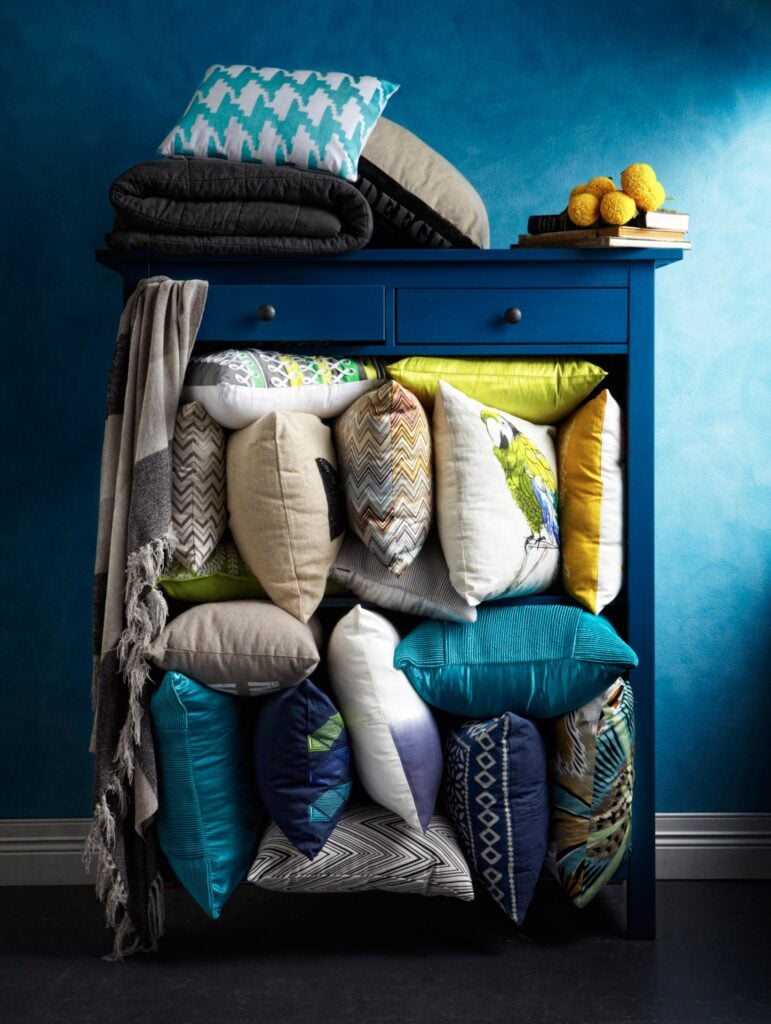Photo by Danella Chalmers of a shelf overflowing with pillows, all in a deep blue or complimenting it.