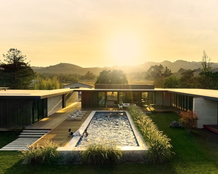 Exterior shot of a house with a swimming pool under the bright sun by Daniel Kelleghan.