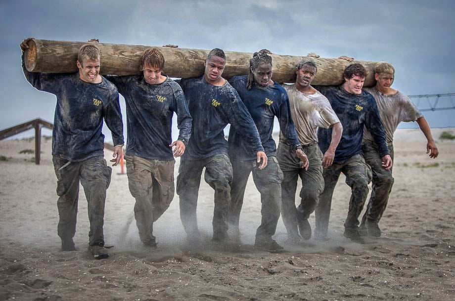 Photo of the The University of Michigan Wolverines football team carrying a log during a training session with the Navy SEALS in San Diego, taken by San Francisco-based fitness photographer Deanne Fitzmaurice. 