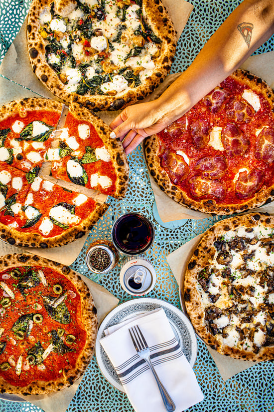 Photo by Drew Anthony Smith of a table of pizzas.