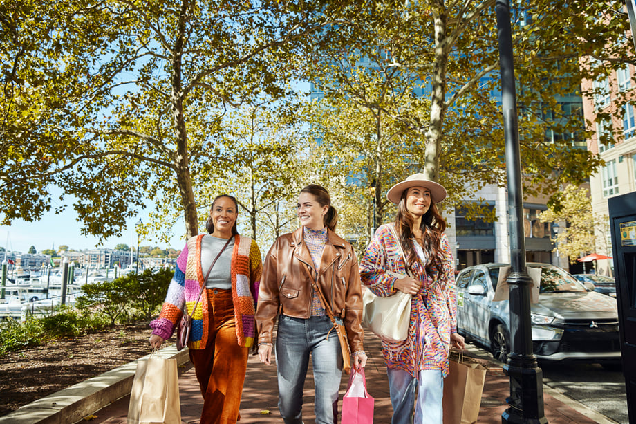 Photo of three women walking along the Harbor East promenade with shopping bags taken by Washington DC-based lifestyle photographer Eli Meir Kaplan. 