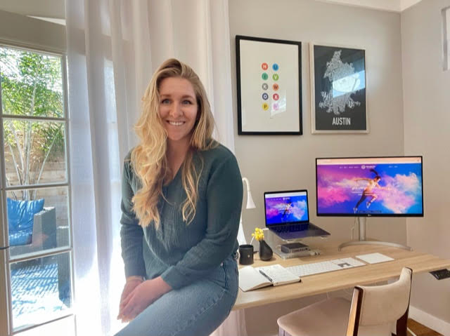 Emily Hoskins smiles in front of her work from home office setup in Long Beach, California.