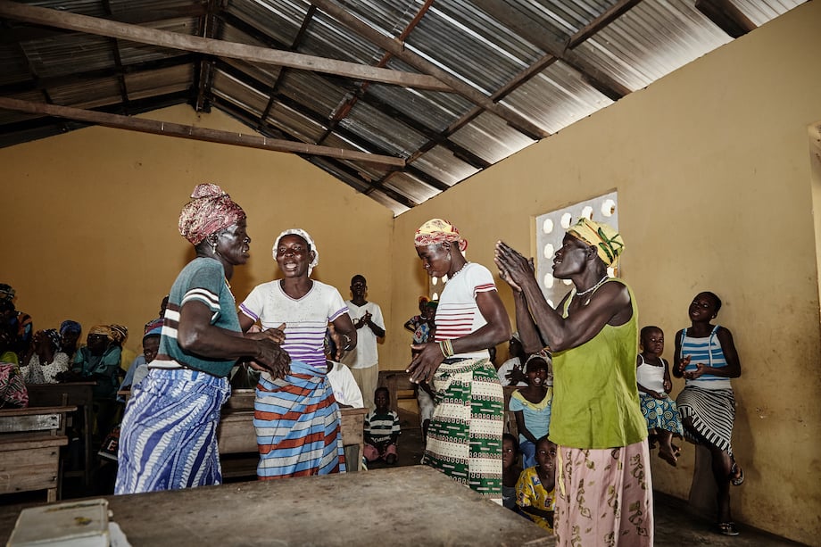 An image of a room filled with Ghanaian women and children singing and clapping.