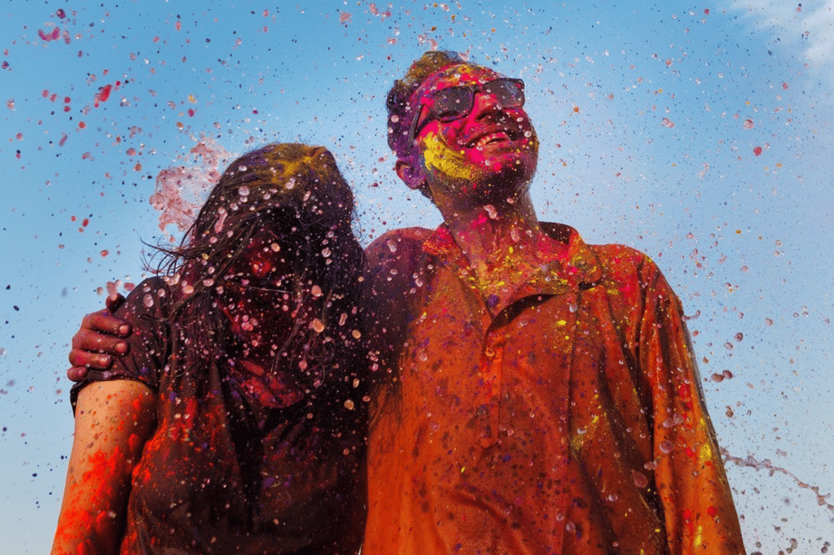 Portrait of two figures smiling (one holding head up, one holding head down) at the sudden onslaught of color, by Mumbai-based portrait photographer Parikshit Rao.