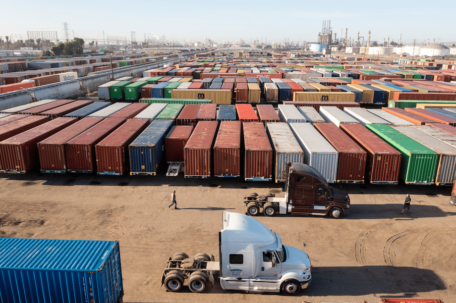 Overview shot of shipping yard filled with colorful shipping containers and industrial buildings in background, by San Diego-based industrial photographer Frank Rogozienski.