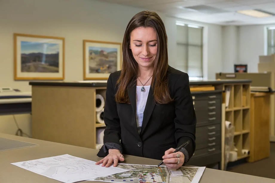 Photo of a female businesswoman circling things on a blueprint map at work taken by Boston-based corporate photographer John Benford. 