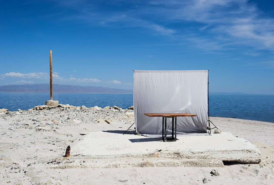 Conceptual portrait of a handcrafted table by the shoreline under blue skies, by Los Angeles product photographer John Cizmas.