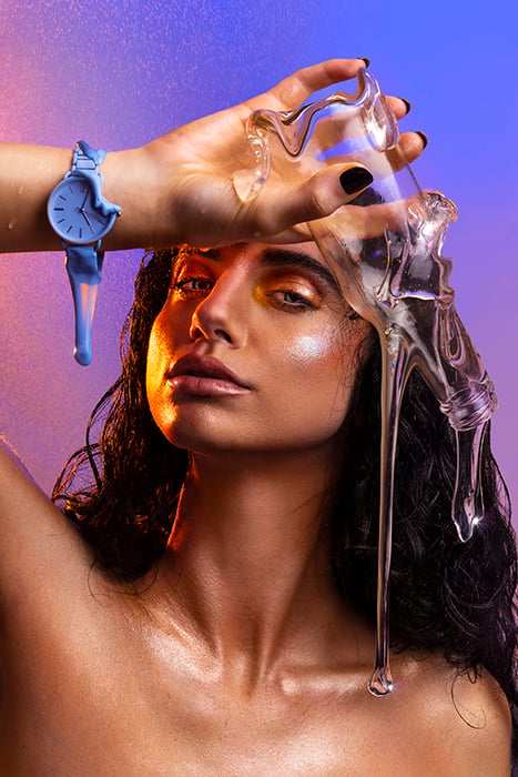 Photo of model holding glass bottle and wearing watch dripping with slime to give melting effect.