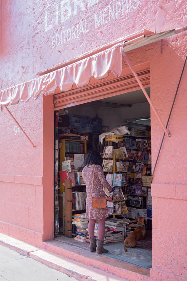 A woman in pink checks out some books at an open air, pink library by photographer Kitt Woodland of Vancouver, Canada