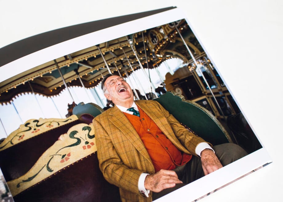 Adam Lerner's new print portfolio open to an image of a man laughing on a merry-go-round.
